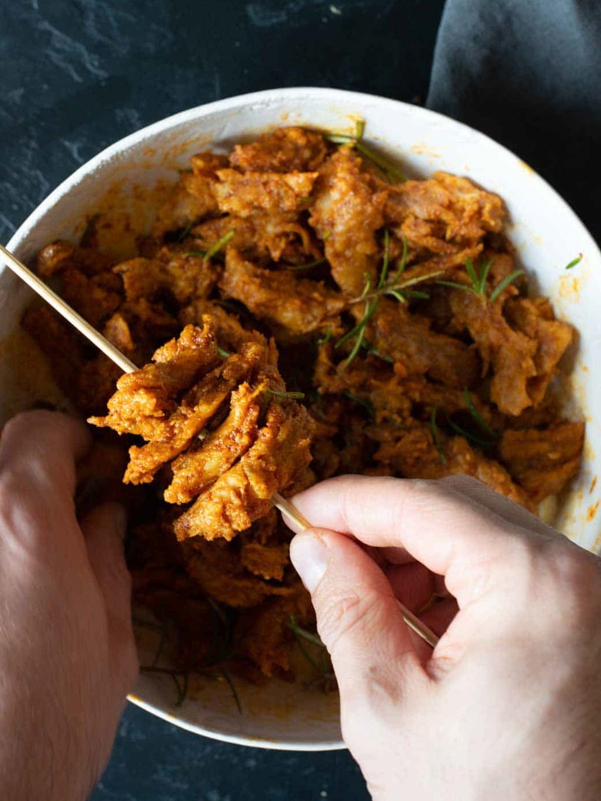 Das Bild zeigt, wie man die Stücke Seitan auf die Spieße steckt.