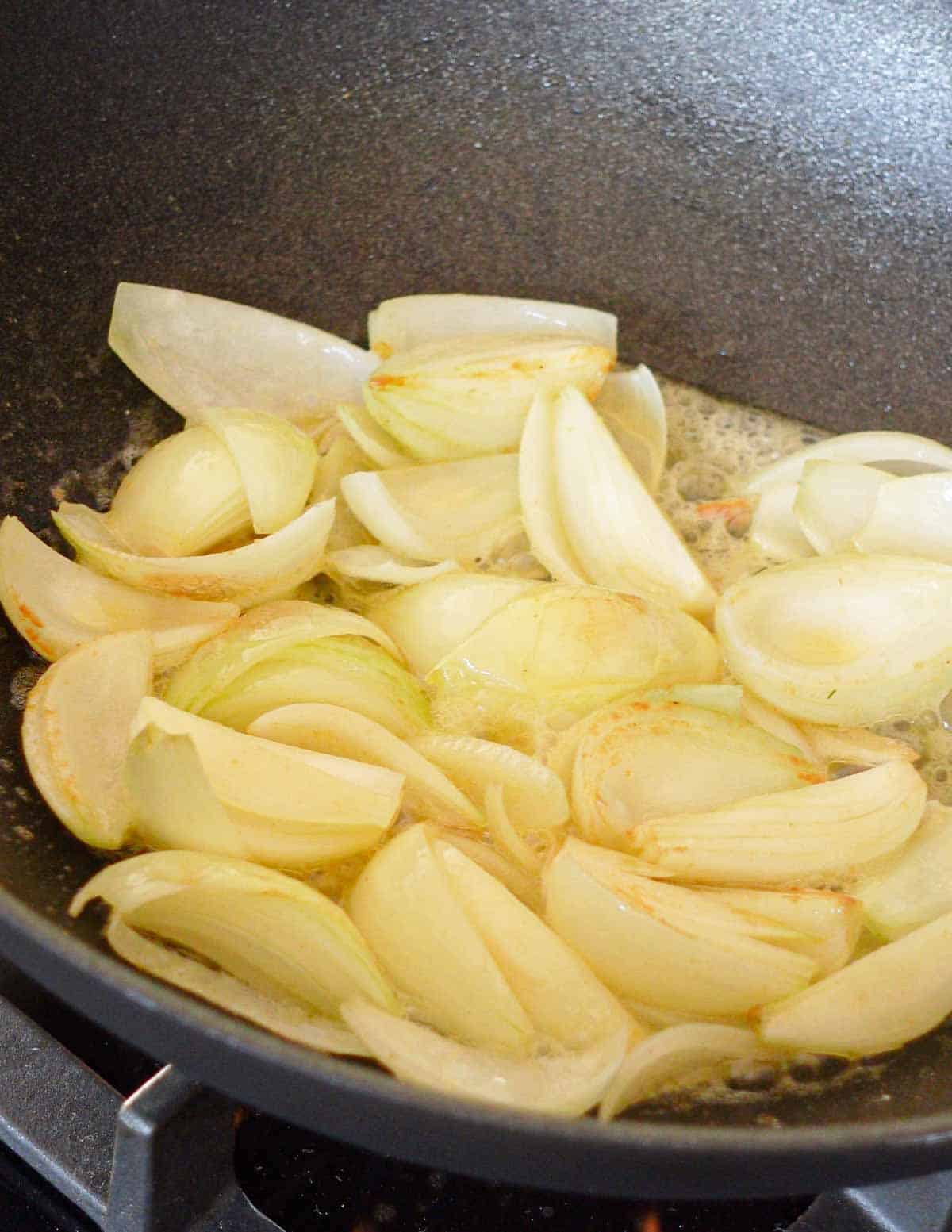 image: onions simmering in a pan