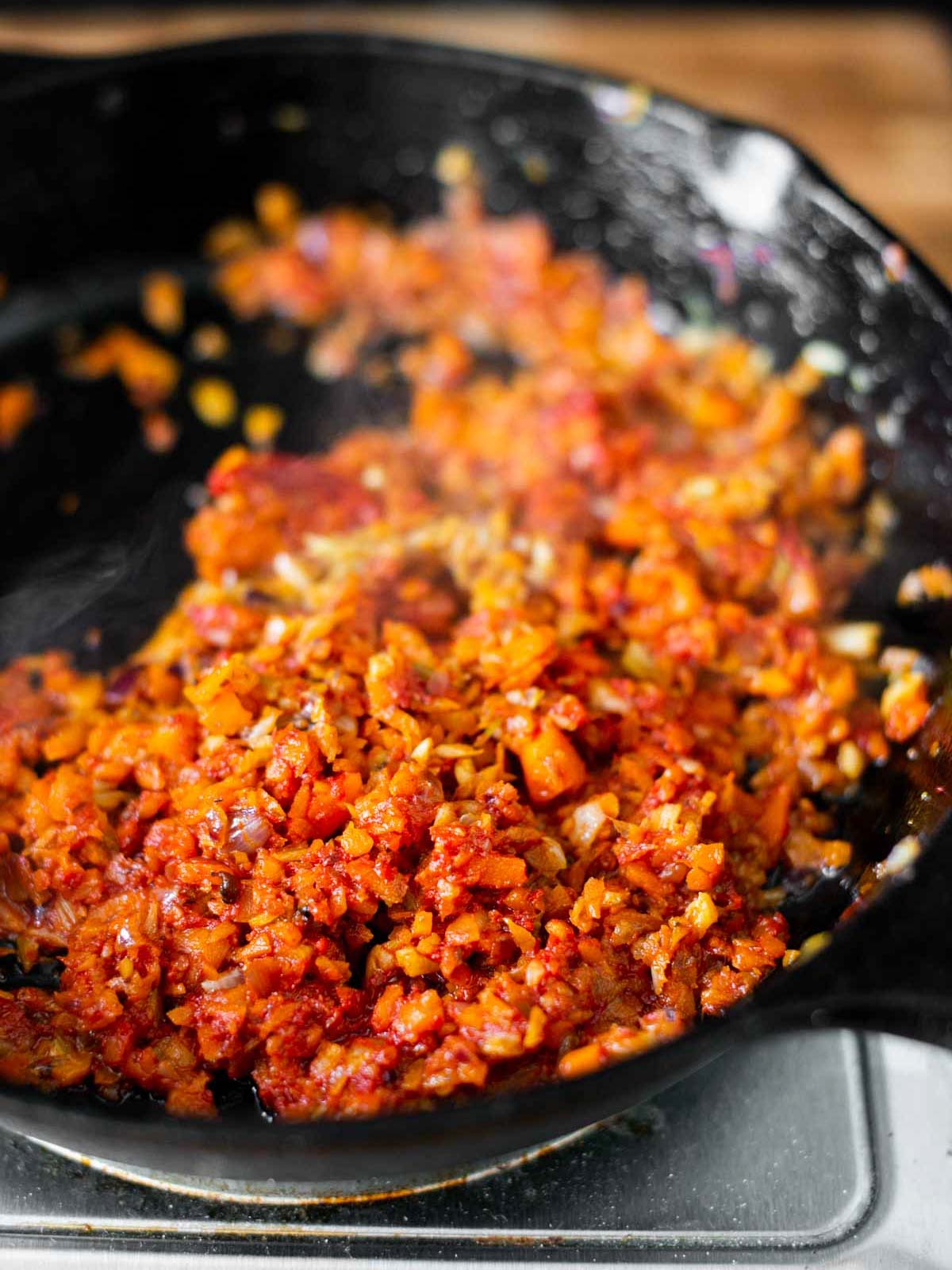 Das Foto zeigt die gehackten Pilze, die in der Pfanne goldbraun gebraten wurden, nach der Zugabe der Tomaten Paste.